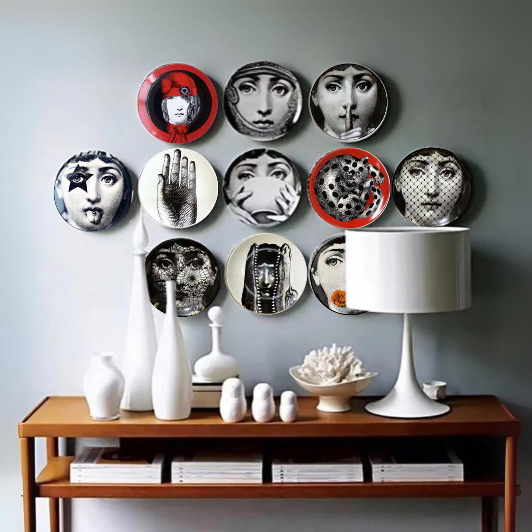 Decorative ceramic wall plates with artistic designs on a gray wall above a wooden console table with decorative items.