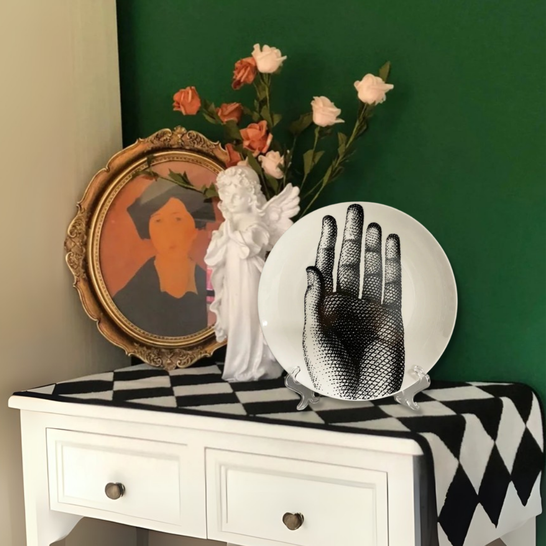 Decorative table with a checkered tablecloth, statue, framed artwork, and decorative ceramic plate against a green wall.