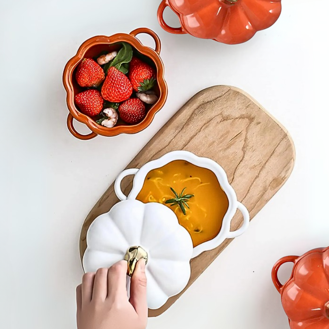 Pumpkin-shaped ceramic bowls with strawberries and soup on a wooden board