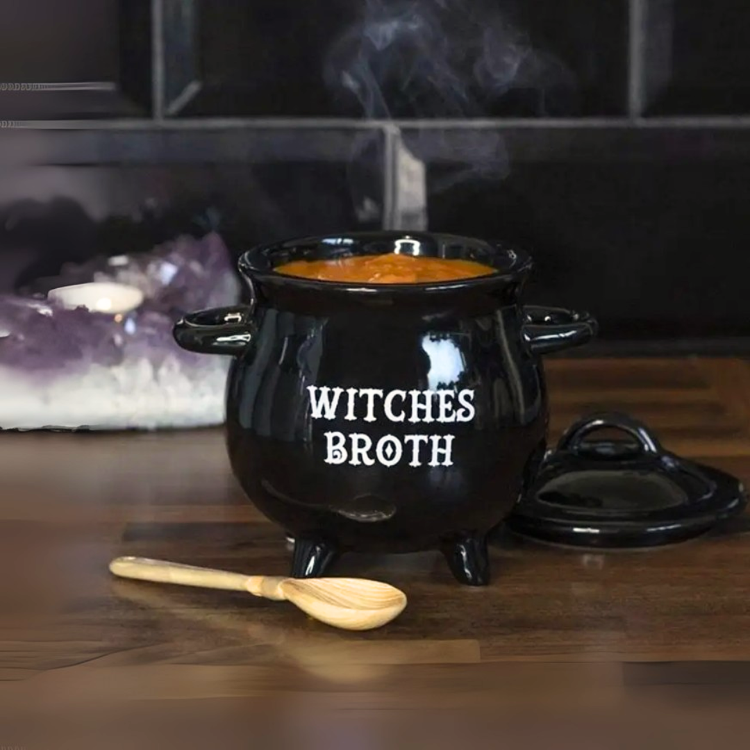 Black cauldron mug with 'Witches Broth' text on a wooden surface with a wooden spoon.