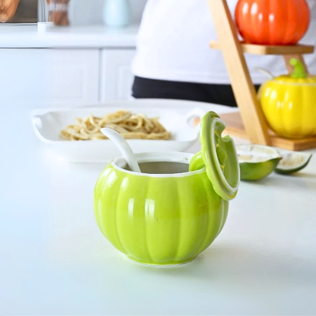 Green ceramic pumpkin-shaped container with a lid on a kitchen counter.
