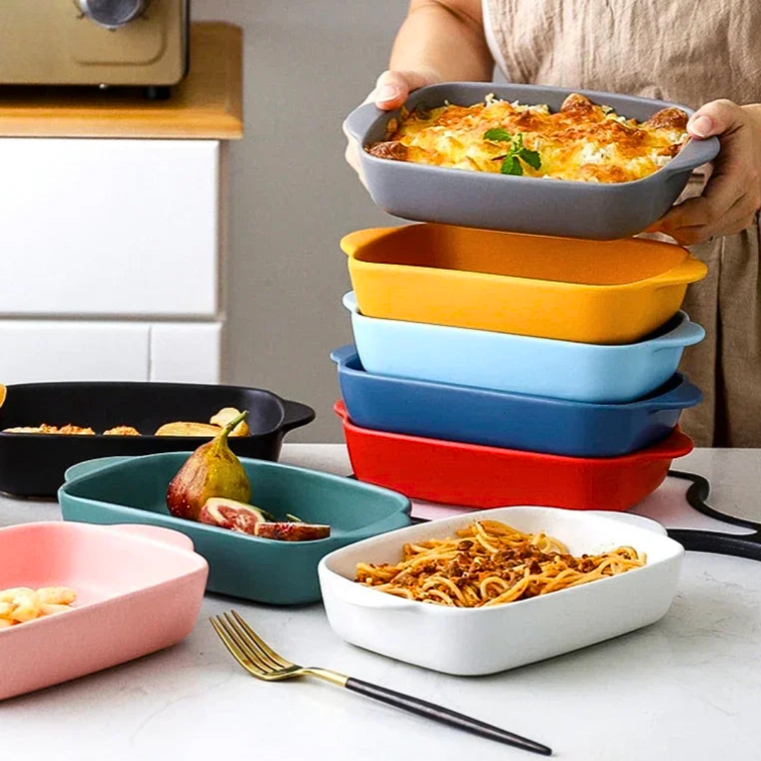 Colorful ceramic baking dishes on a kitchen counter with food.