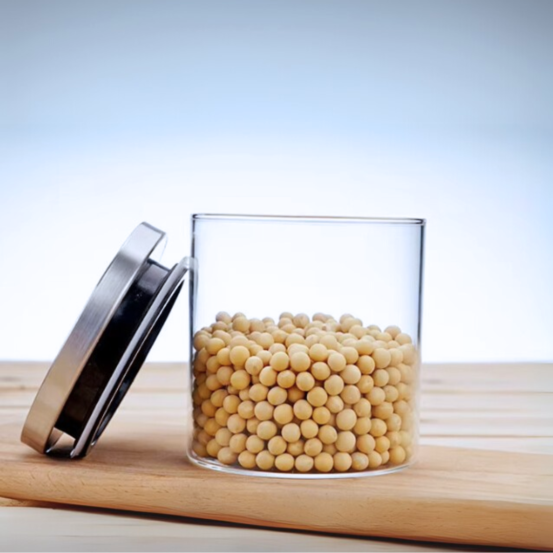 Glass jar with airtight stainless steel lid filled with soybeans on a wooden tray.