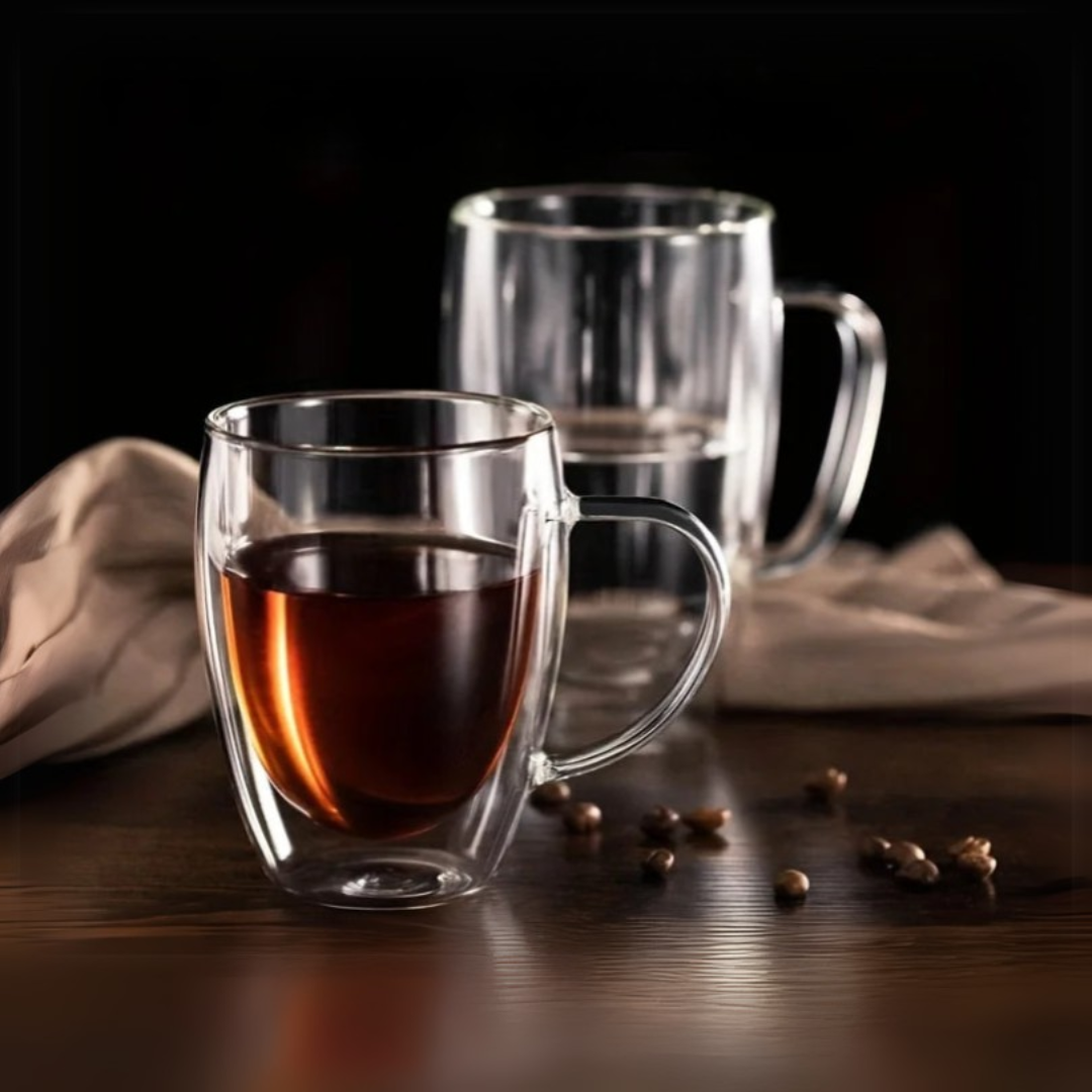 Two clear glass mugs on a wooden table with one containing coffee and coffee beans around.