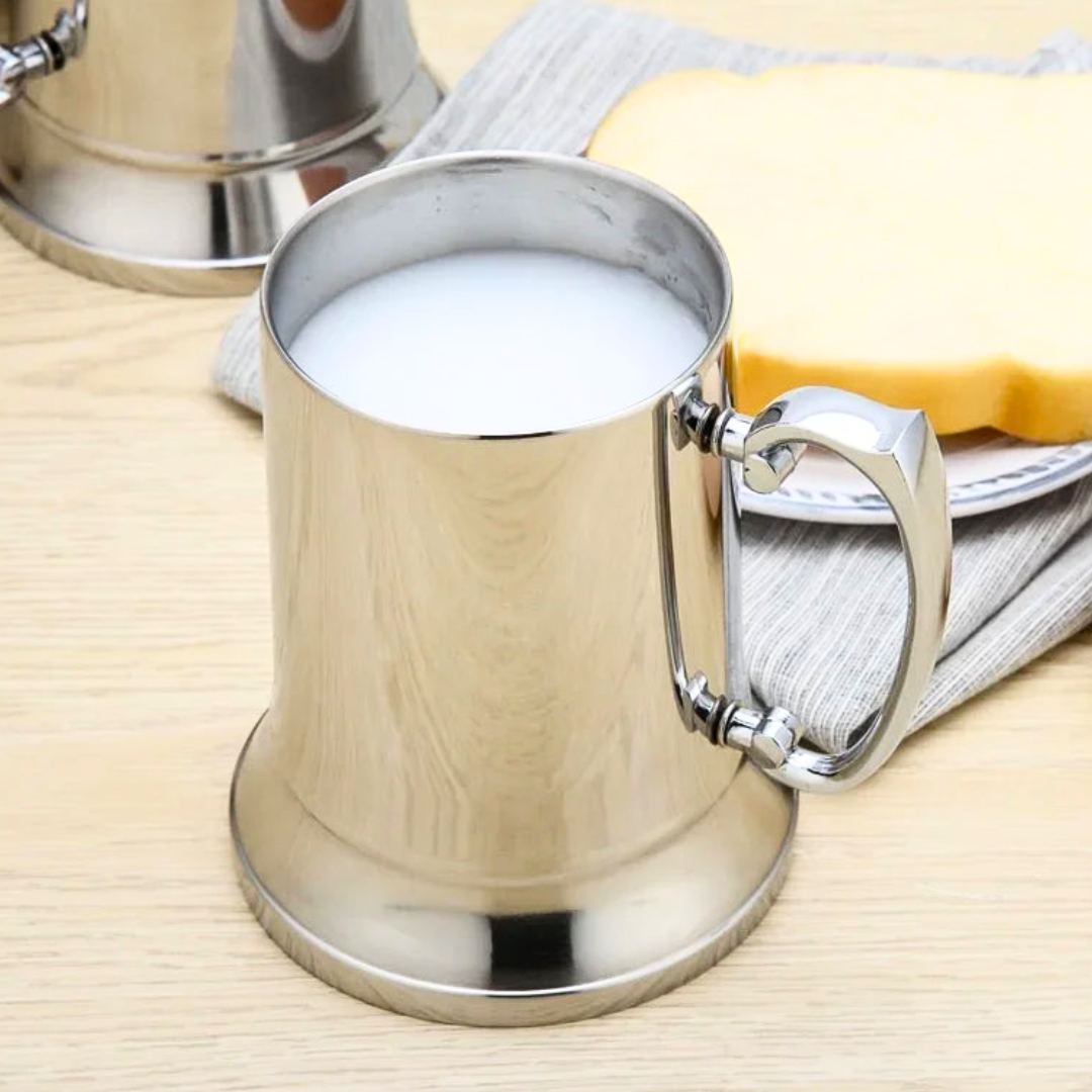 Stainless steel mug filled with milk on a wooden table