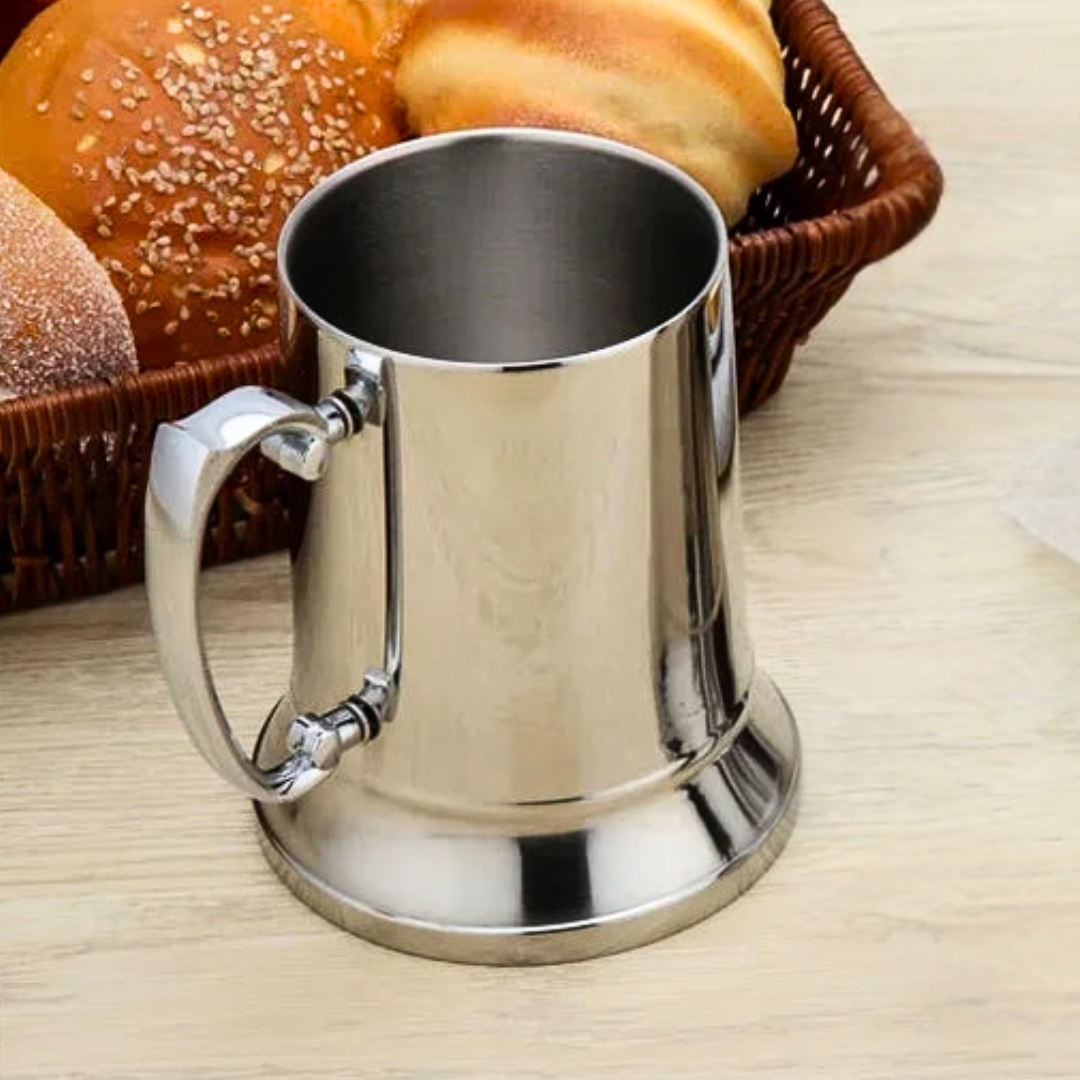 Stainless steel tumbler on a wooden table with bread in the background