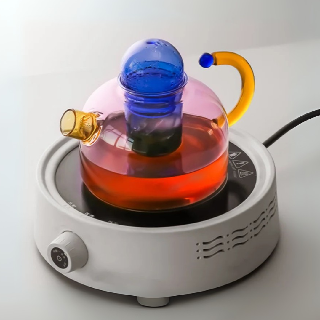 Glass tea kettle with a blue lid on a white base, filled with tea.