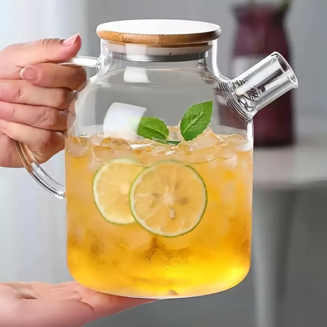Clear glass pitcher filled with iced lemonade, held by a hand.