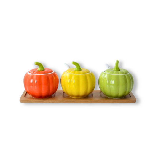 Three colorful ceramic pumpkin-shaped containers on a wooden tray